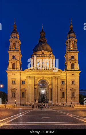Vu d'un angle vertical bas au crépuscule, la façade dorée illuminée de la basilique Saint-Étienne s'élève à travers des rangées de colonnes corinthiennes et un clocher jumeau Banque D'Images