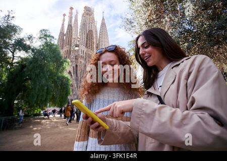 Deux femmes souriantes amies en utilisant le téléphone pour recueillir. Banque D'Images