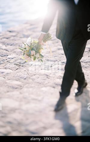 Homme en costume tenant un bouquet de mariage en plein air Banque D'Images