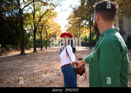 Femme tenant la main de son partenaire, souriant dans un parc d'automne Banque D'Images