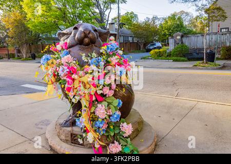 Arkansas, États-Unis, 07 AVR 2024 - Une sculpture d'écureuil en bronze repose sur une base en pierre, drapée dans une guirlande vibrante de rose, bleu et jaune Banque D'Images