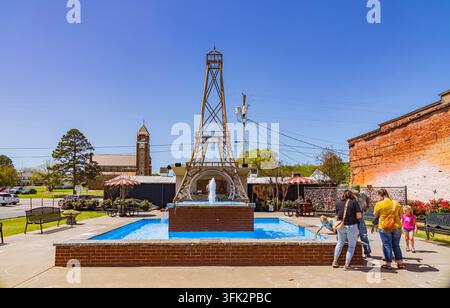 Arkansas, États-Unis, 07 AVR 2024 - Une fontaine centrale jaillit vers le haut dans une place bordée de briques entourée de bâtiments historiques et de gens Banque D'Images