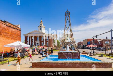 Arkansas, États-Unis, 07 avr. 2024 - Une fontaine d’eau bleu vif jaillit au centre d’une place animée sous un ciel bleu clair. Banque D'Images