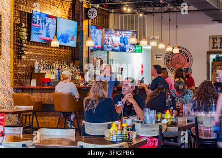 Arkansas, États-Unis, 07 avr. 2024 - Les clients sont assis à des tables en bois et boivent dans un pub chaleureux et faiblement éclairé, doté d'une décoration murale en cuivre et de plusieurs Banque D'Images