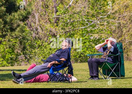 Arkansas, États-Unis, 08 avr. 2024 - Deux hommes âgés se prélassent dans des chaises pliantes sur une pelouse d'herbe verte brillante entourée d'arbres luxuriants du printemps. Banque D'Images