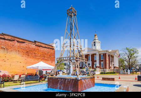 Arkansas, États-Unis, 07 AVR 2024 - L'eau jaillit d'une base de fontaine en brique sous une structure métallique imposante dans une place urbaine lumineuse. Banque D'Images