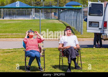 Arkansas, États-Unis, 08 AVR 2024 - Un couple âgé est assis sur des chaises de jardin dans un champ herbeux tout en portant des lunettes de protection pour éclipse solaire sous Banque D'Images