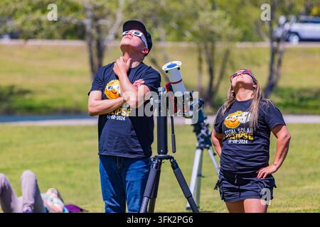 Arkansas, États-Unis, 08 AVR 2024 – Un homme et une femme se tiennent dans un champ herbeux à côté d’un télescope tout en regardant le ciel lors d’une éclipse solaire Banque D'Images