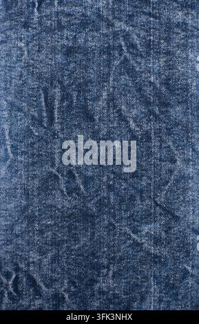 Fond vertical en gros plan d'un tissu denim bleu usé avec des fibres délavées et des détails textiles de jeans classiques. Banque D'Images