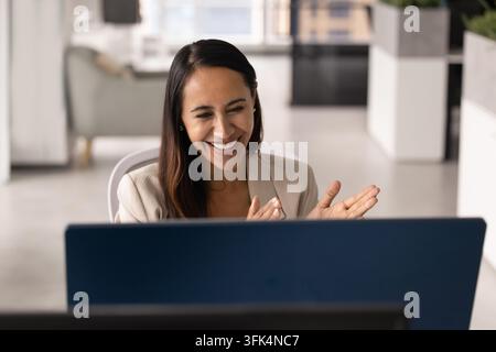 Femme d'affaires joyeuse participant à une réunion en visioconférence au bureau Banque D'Images