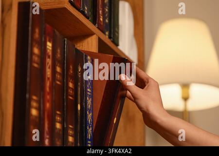 Éducation et apprentissage tout au long de la vie, personne choisissant un livre sur une étagère en bois de bibliothèque pour la recherche et l'étude académique dans un environnement calme de bureau à domicile Banque D'Images