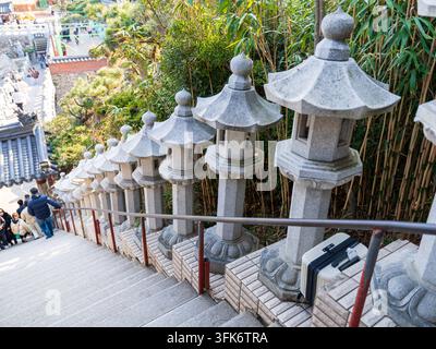 Busan, Corée du Sud - 14 février 2026 : Vue du temple Haedong Yonggungsa présentant une rangée de lanternes en pierre traditionnelles bordant l'escalier avec du bambou Banque D'Images