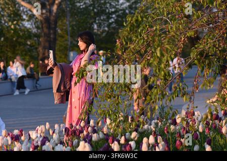 Fille en robe rose prenant un selfie dans un jardin de tulipes Banque D'Images