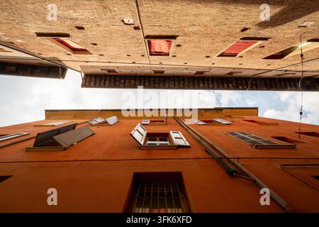 Bologne, Italie - 17 mai 2018 : Vue sur les bâtiments historiques orange avec volets ouverts et détails architecturaux dans le centre-ville. Banque D'Images