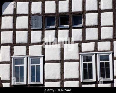 gros plan d'une façade historique en colombage avec des panneaux de plâtre blanc et des poutres en bois sombre, présentant de petites fenêtres à Steinau. Banque D'Images