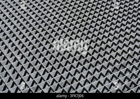 Motif abstrait de lumière et d'ombre sur une grille métallique avec des motifs géométriques de triangles Banque D'Images