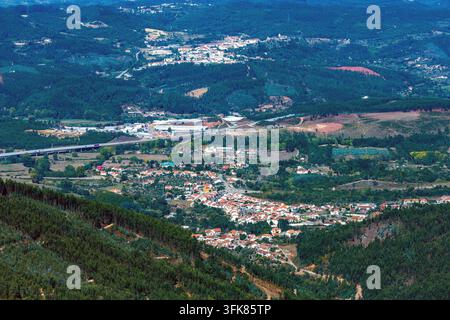 Une vue aérienne révèle de petits villages et des routes sinueuses nichés dans une vaste vallée montagneuse verdoyante lors d'une randonnée au Portugal. Banque D'Images