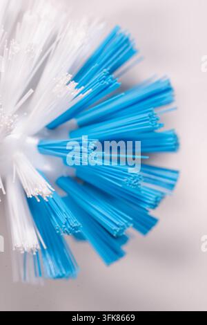 Extrême gros plan des poils denses d'une brosse créant une texture répétitive et un motif industriel en blanc et bleu Banque D'Images