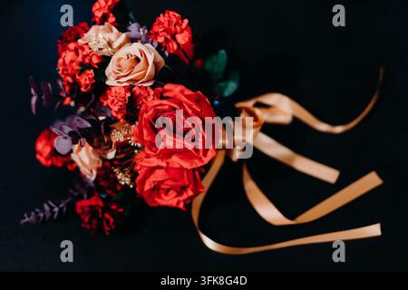 Bouquet de roses rouges de luxe avec ruban en satin doré sur fond sombre Banque D'Images