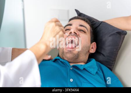Homme atteint de paralysie cérébrale recevant une stimulation orale d'un thérapeute pour la rééducation Banque D'Images