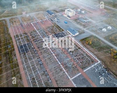 Vue aérienne d'une sous-station électrique haute tension avec des lignes de puissance complexes, des transformateurs et des bâtiments industriels entourés de forêt à Muhos, Nor Banque D'Images