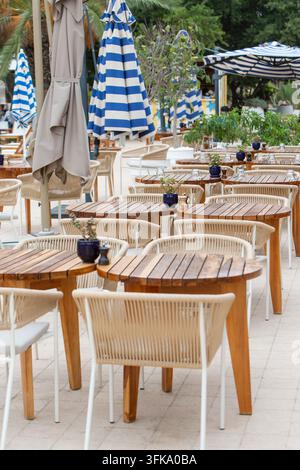 Tables et chaises d'extérieur élégantes dans un complexe hôtelier de luxe. Espace de restauration extérieur stylé dans un complexe hôtelier moderne avec des tables en bois Banque D'Images