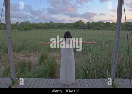 Femme joyeuse les bras tendus sur une promenade en bois Banque D'Images