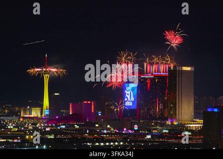 Des feux d'artifice colorés illuminent le ciel nocturne au-dessus du Strip de Las Vegas dans le Nevada, avec la tour Stratosphere et les grands hôtels brillant intensément. La fête Banque D'Images