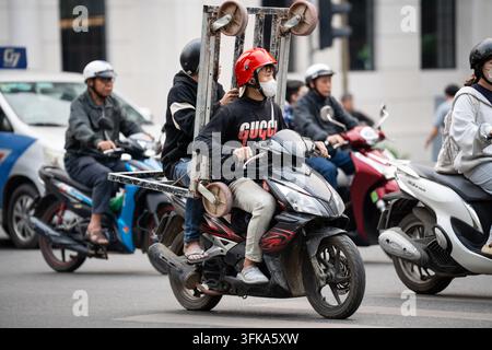 Heure de pointe animée sur la route de la ville de Hanoï, des gens sur des scooters et des motos circulent sur la chaussée. Banque D'Images
