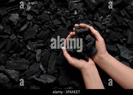 Durabilité et ressources énergétiques, personne tenant du charbon de bois naturel en morceaux pour barbecue ou production de carburant industriel en gros plan vu de dessus Banque D'Images