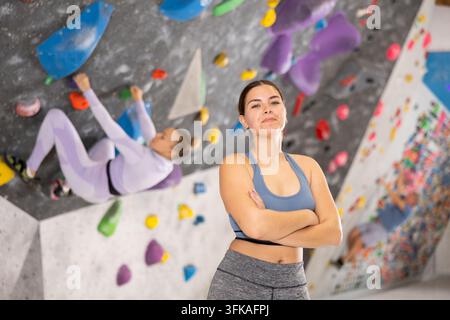 Jeune femme athlétique en vêtements de sport posant sur le mur d'escalade Banque D'Images
