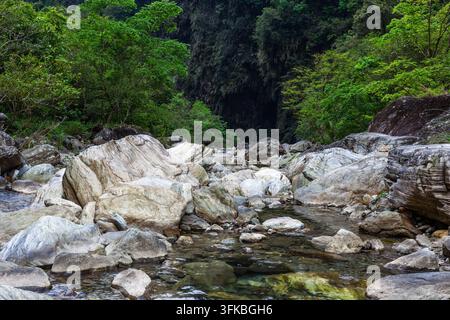 Rivière Sanzhanxi dans le parc national de Taroko. De gros rochers texturés se trouvent dans un ruisseau de montagne clair. Une forêt luxuriante couvre les collines environnantes. Banque D'Images