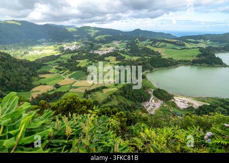 Panorama élevé et étendu d'une vallée montagneuse verdoyante, capturé depuis un point de vue élevé. Au premier plan, un feuillage tropical vibrant avec des larges Gr Banque D'Images