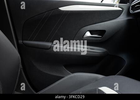 Photographie intérieure d'un panneau de porte passager moderne de voiture avec revêtement en tissu sombre, coutures blanches contrastées, poignée de porte en argent et accoudoir Banque D'Images