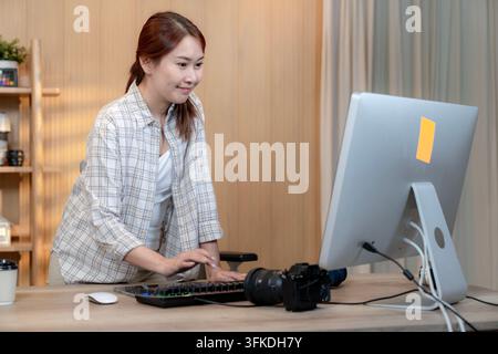 Une jeune femme travaillant sur son ordinateur portable tout en étant confortablement assise dans un environnement de bureau moderne et lumineux à domicile. Banque D'Images
