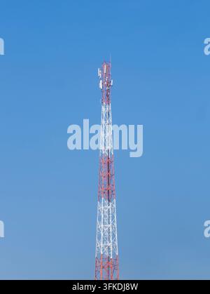Tour de communication rouge et blanche contre un ciel bleu, représentant la communication sans fil, l'infrastructure de diffusion, la technologie et le réseau Banque D'Images