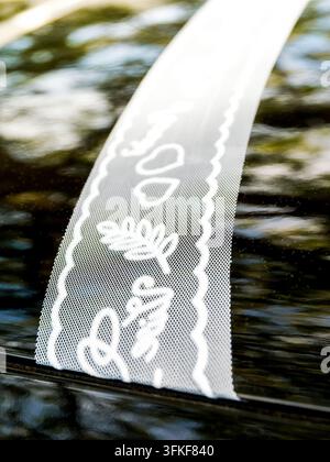 Ruban de dentelle décoratif blanc avec motifs de cœur et floraux réfléchi sur une surface sombre Banque D'Images