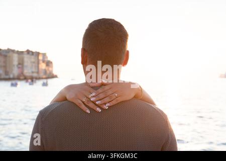 Jeune couple enlacé au coucher du soleil Banque D'Images