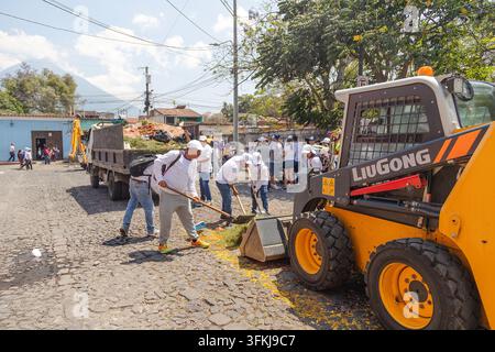 Des ouvriers nettoient les restes des alfombras de la Semaine Sainte sur une rue pavée après une procession à Antigua Guatemala le 13 avril 2025. Banque D'Images