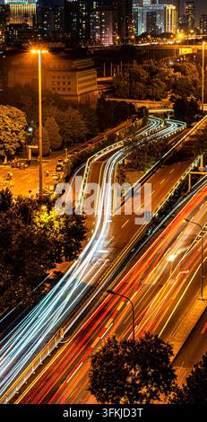 Pont d'autoroute urbaine de Pékin la nuit avec traînées de lumière des véhicules et bannières verticales Banque D'Images