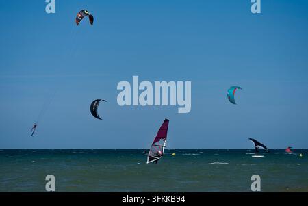 Langrune-Sur-Mer, France - 08 08 2026 : Les windsurfeurs et les kitesurfeurs sont et sautent dans la mer sous un ciel bleu Banque D'Images