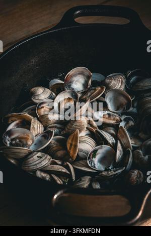 Présentation en gros plan de palourdes cuites à la vapeur dans une marmite rustique en fonte Banque D'Images