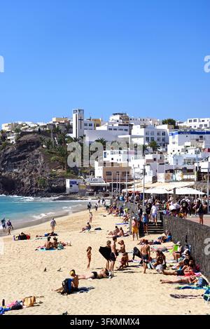 Touristes se relaxant le long de la promenade et de la plage avec des bars et des restaurants à l'arrière-plan, Morro Jable, Fuerteventura. Banque D'Images