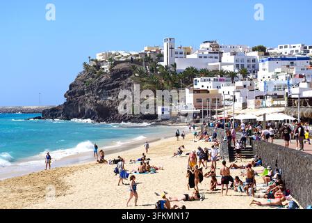 Touristes se relaxant le long de la promenade et de la plage avec des bars et des restaurants à l'arrière-plan, Morro Jable, Fuerteventura. Banque D'Images