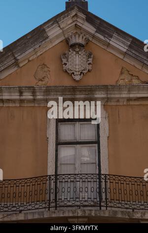 Façade historique ornée à Lisbonne, Portugal, présentant un fronton décoré, des détails sculpturaux et un balcon en fer forgé. Banque D'Images