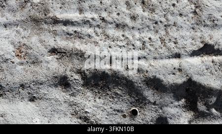 Texture de béton gris rugueux avec des stries horizontales sombres et des trous éparpillés et piqués Banque D'Images