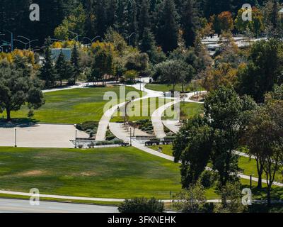 Une vue aérienne révèle des allées en béton sinueuses traversant des pelouses et des arbres paysagés dans un parc ensoleillé du campus d'entreprise de Google à Mountain View, Californie Banque D'Images