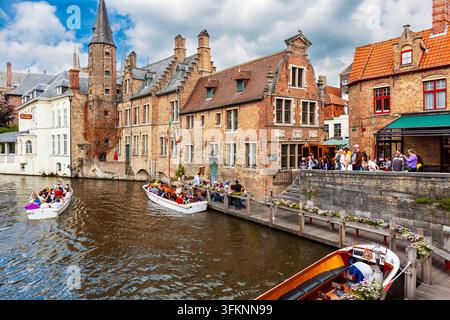 Bruges, Belgique - 20 juillet 2011 : Navigation de bateaux sur le canal Dijver. De petits bateaux de tourisme quittent un port à un virage du canal Dijver tandis que d'autres touristes attendent. Banque D'Images