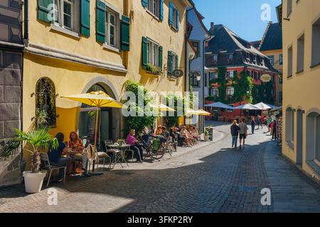 Vue de la Steigstrasse historique et ensoleillée avec ses façades colorées, ses maisons à pans de bois et ses restaurants en terrasse, où les piétons suivent le a pavé Banque D'Images