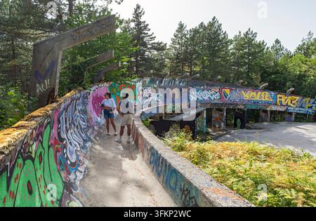 Visiteurs marchant le long de la piste de bobsleigh abandonnée de 1984 couverte de graffitis sur le mont Trebevic, à Sarajevo, Bosnie-Herzégovine Banque D'Images